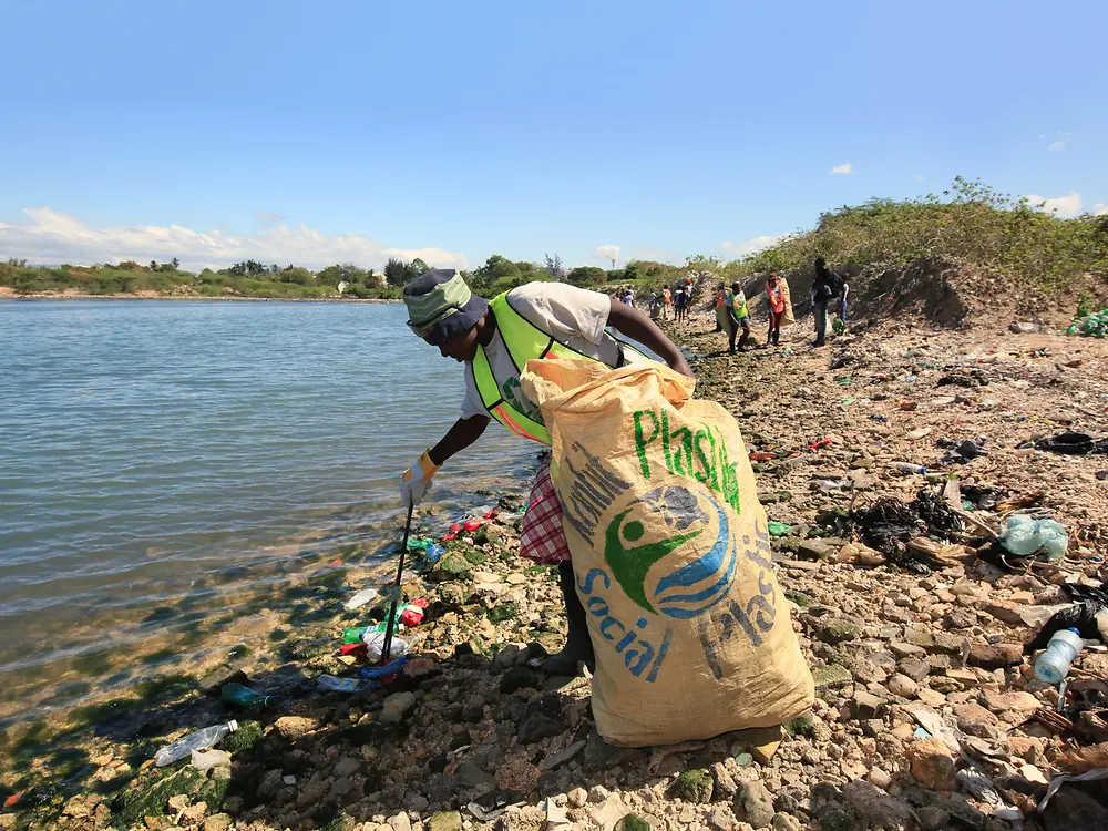 Woman collecting plastic waste on beach in Haiti